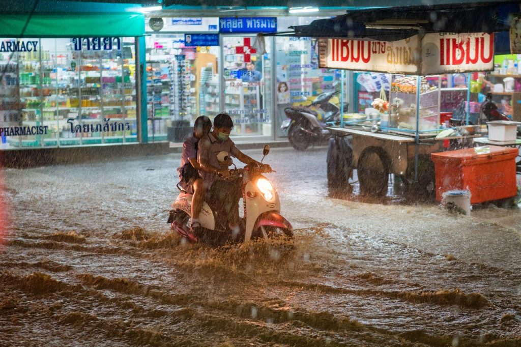 Người đi xe máy cố gắng vượt qua con đường ngập nước dưới cơn mưa lớn ở TP.