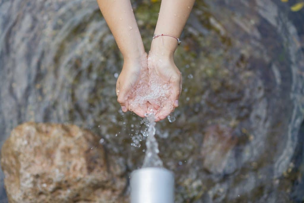 Vòi phun ra nước rất sạch.  Bàn tay phụ nữ đang nhận nước này chảy ra từ vòi và nó rơi xuống tạo thành một vũng nước.
